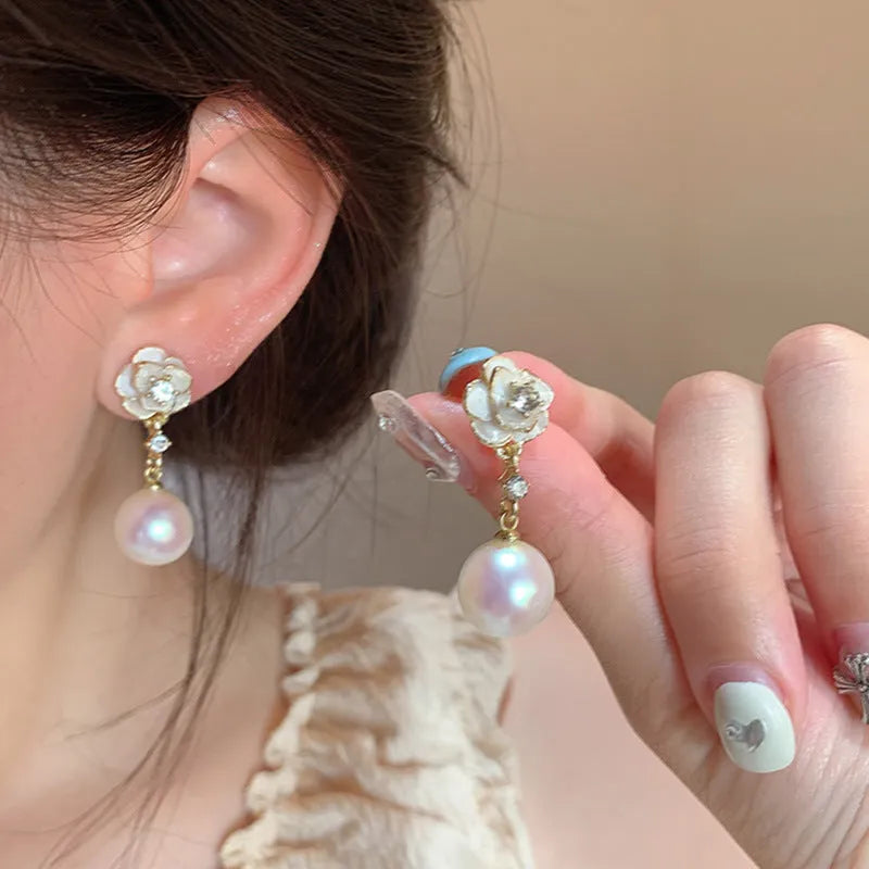 A pair of camellia flower-shaped alloy stud earrings for women on a white background.