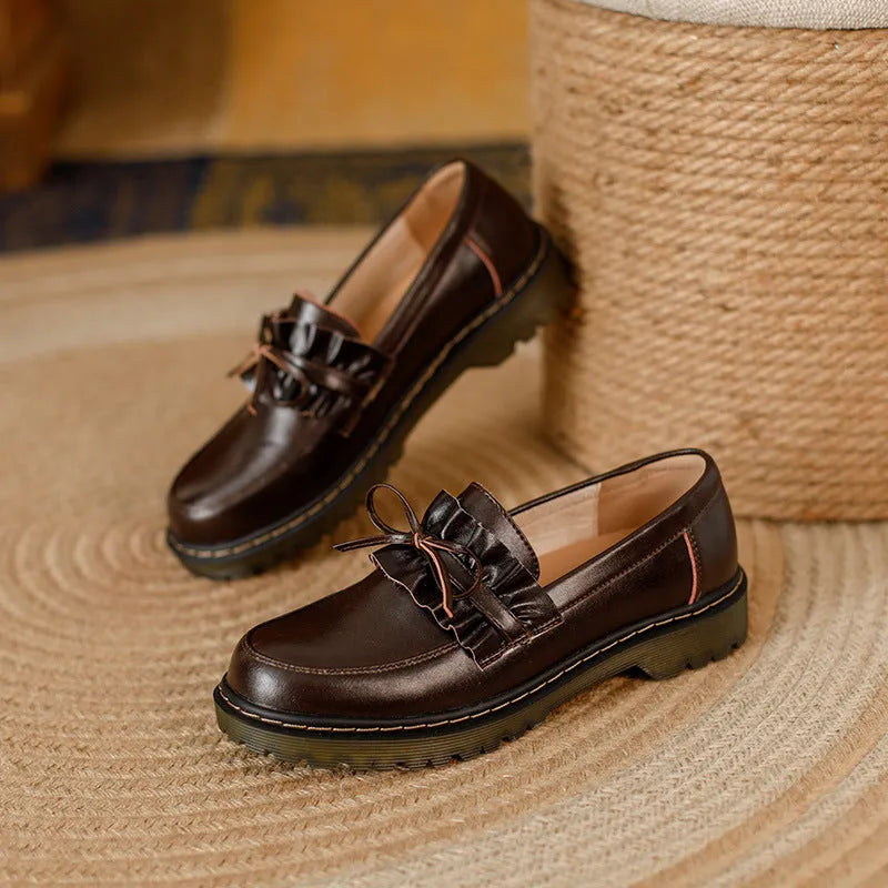 Women's black leather chunky heel shoes with a round toe on a neutral background.
