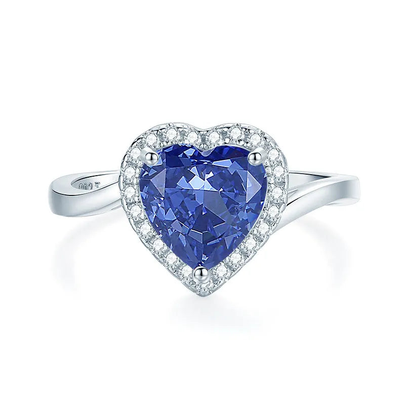 Women's heart-shaped sterling silver ring with ice flower cut coloured zircon stone on finger.