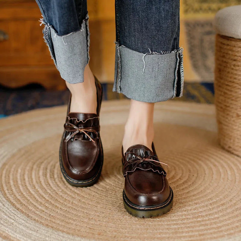 Women's black leather chunky heel shoes with a round toe on a neutral background.