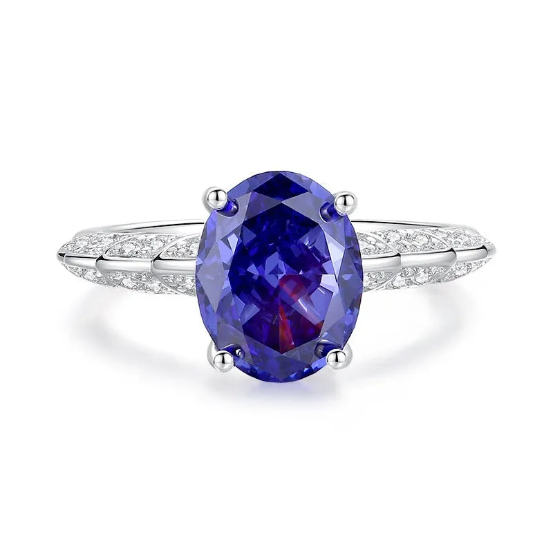 Women's heart-shaped sterling silver ring with ice flower cut coloured zircon stone on finger.