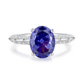 Women's heart-shaped sterling silver ring with ice flower cut coloured zircon stone on finger.