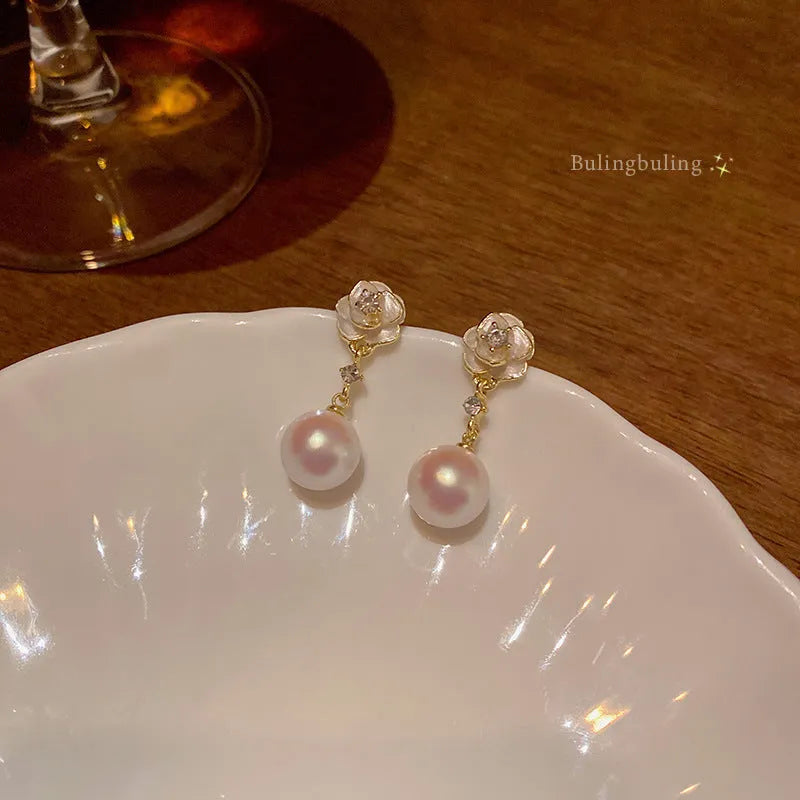 A pair of camellia flower-shaped alloy stud earrings for women on a white background.