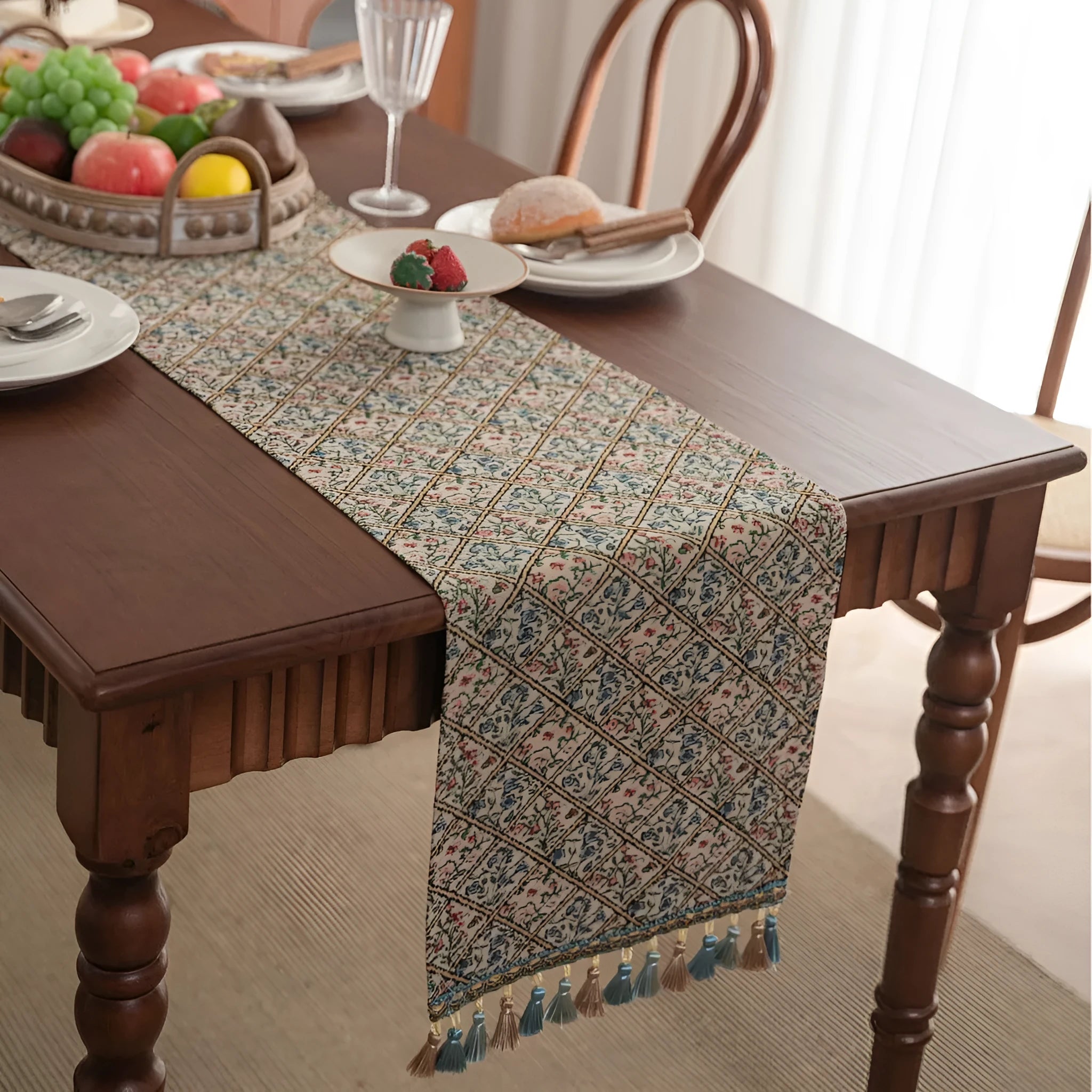 Dark blue and white striped jacquard table runner with tassel trim laid on a wooden dining table.