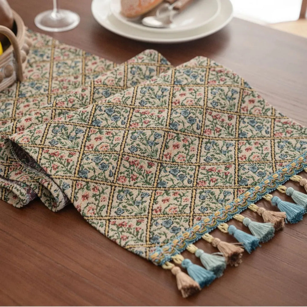 Dark blue and white striped jacquard table runner with tassel trim laid on a wooden dining table.