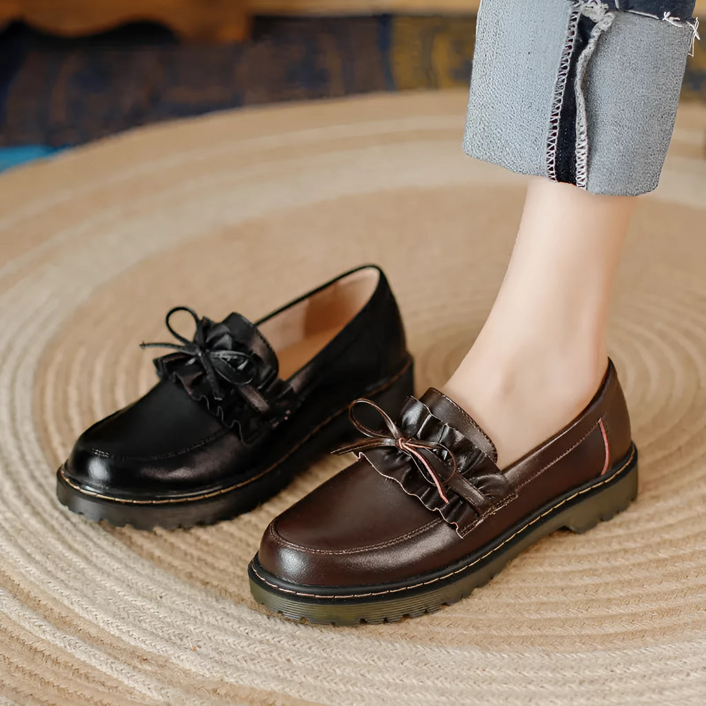 Women's black leather chunky heel shoes with a round toe on a neutral background.