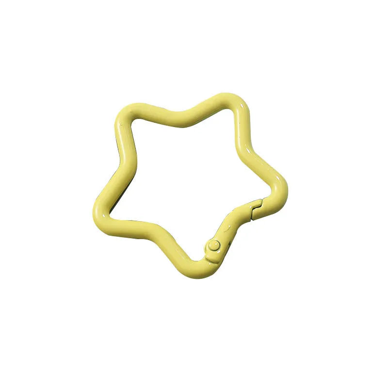 Zinc alloy five-pointed star keychain in light pink colour on a black background.