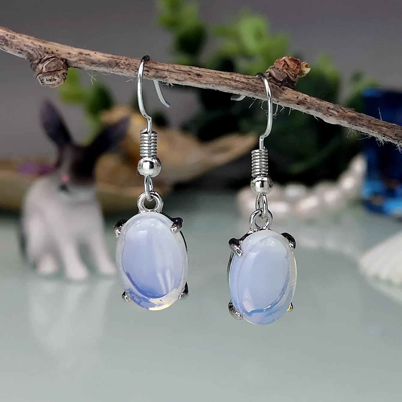 A pair of retro-style drop earrings with a moonlight opal colour and simple cross detail.