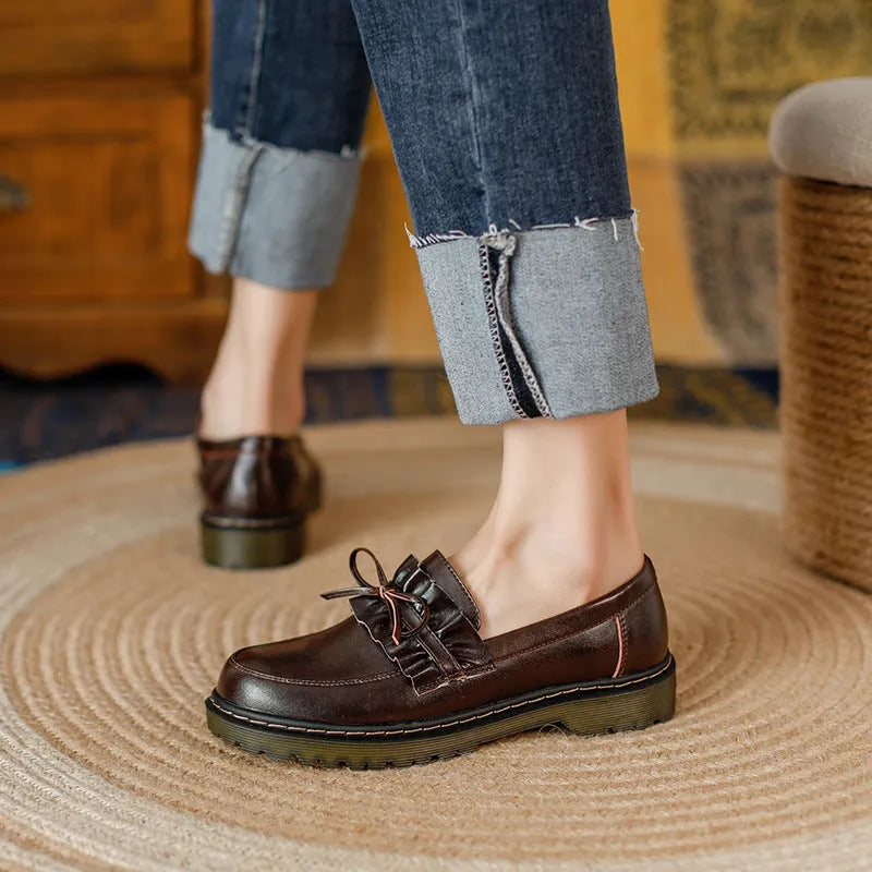 Women's black leather chunky heel shoes with a round toe on a neutral background.
