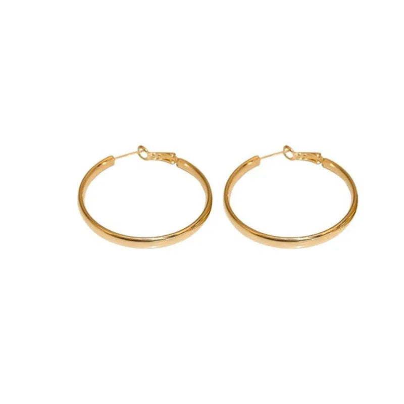 A pair of simple metal circle hoop earrings in a gold colour against a plain background.