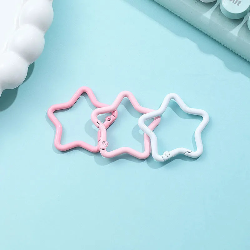 Zinc alloy five-pointed star keychain in light pink colour on a black background.