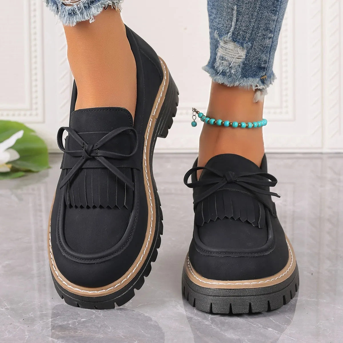 Women's black plus size loafers with tassel and bowknot detail on a chunky rubber sole.