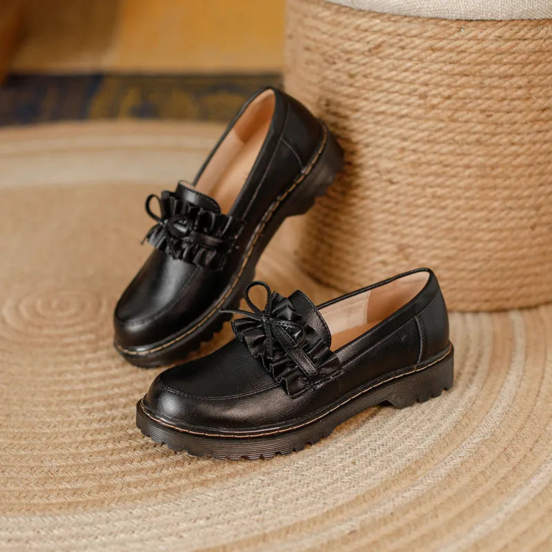 Women's black leather chunky heel shoes with a round toe on a neutral background.