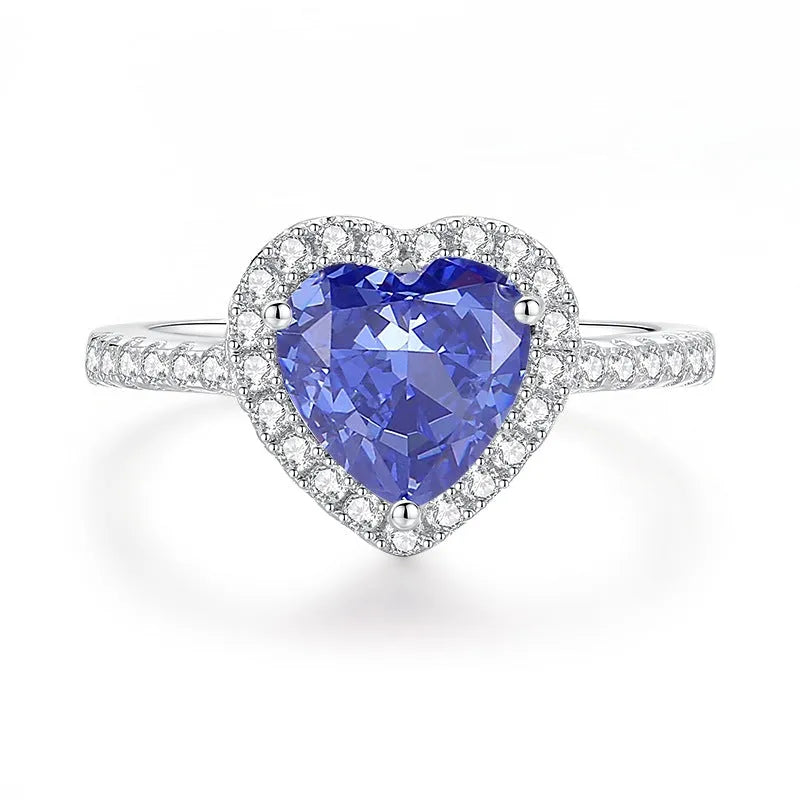Women's heart-shaped sterling silver ring with ice flower cut coloured zircon stone on finger.