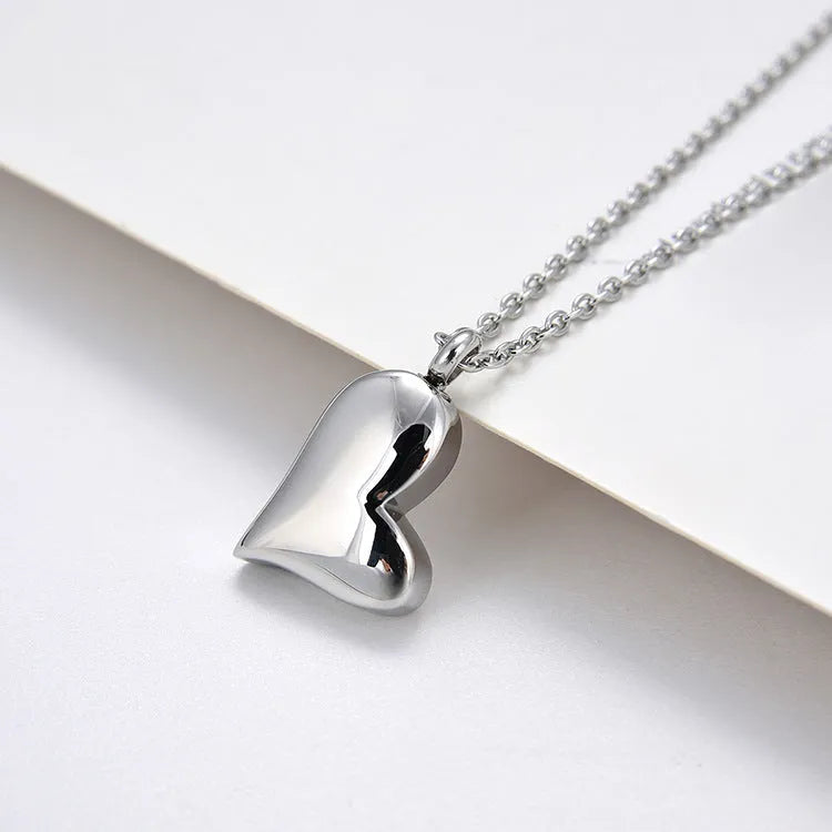 Silver curved peach heart stainless steel pendant necklace on a model, showing the adjustable chain length.