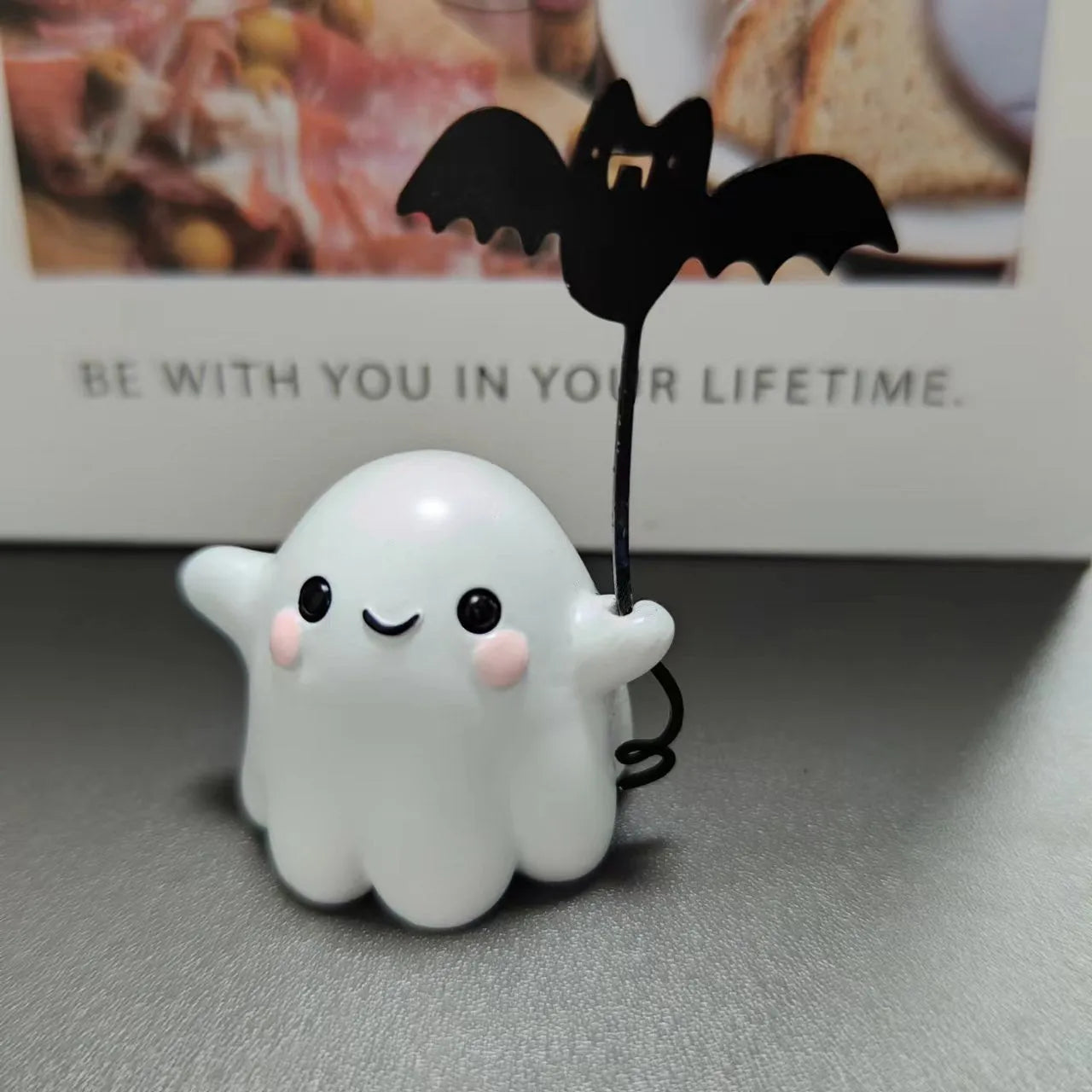 Small resin statue of a ghost holding a bat while walking a dog, a Halloween decoration.
