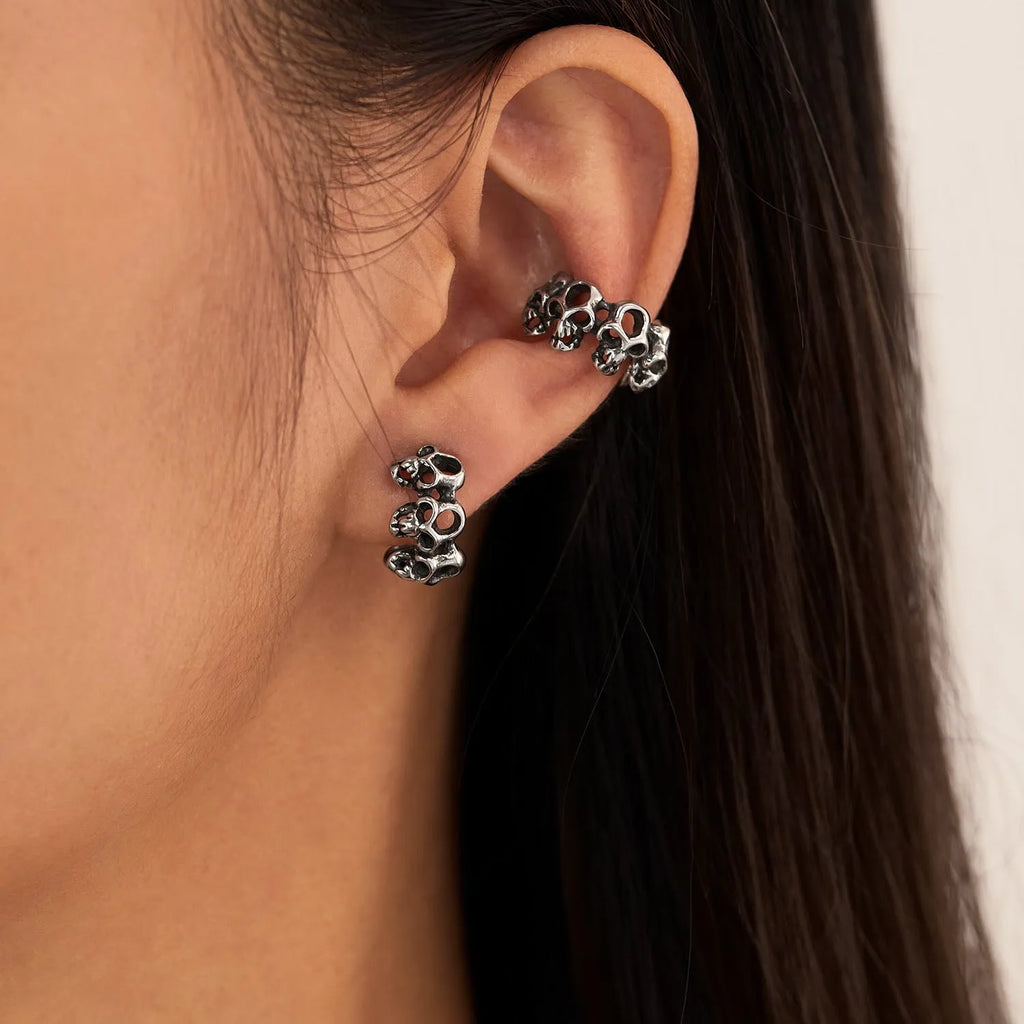 Stainless steel skull earrings with geometric hollow design and clip fitting in metallic finish