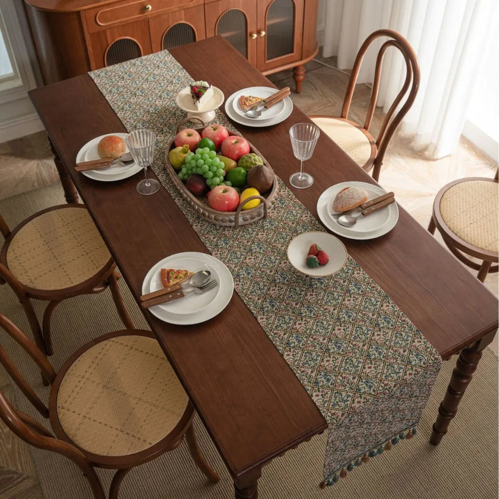 Dark blue and white striped jacquard table runner with tassel trim laid on a wooden dining table.