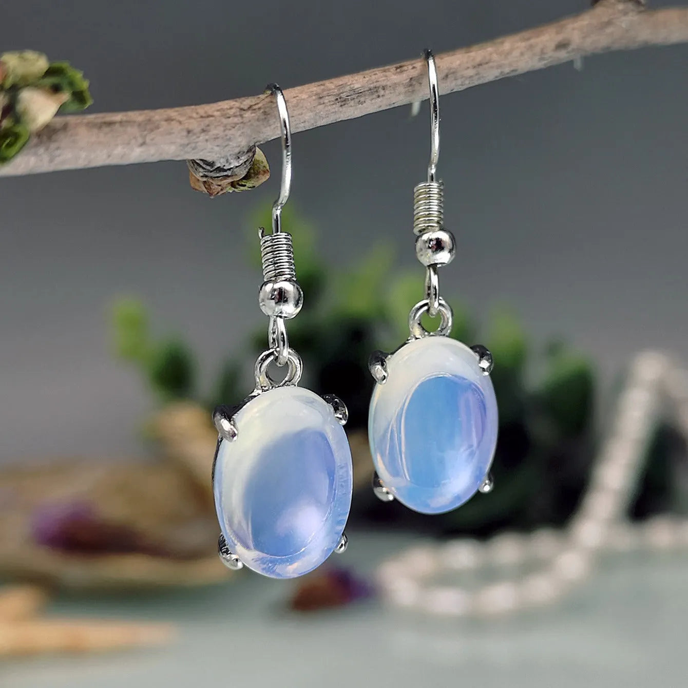A pair of retro-style drop earrings with a moonlight opal colour and simple cross detail.