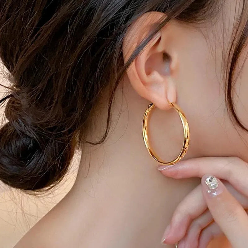 A pair of simple metal circle hoop earrings in a gold colour against a plain background.
