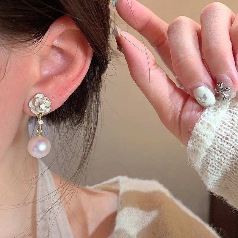 A pair of camellia flower-shaped alloy stud earrings for women on a white background.