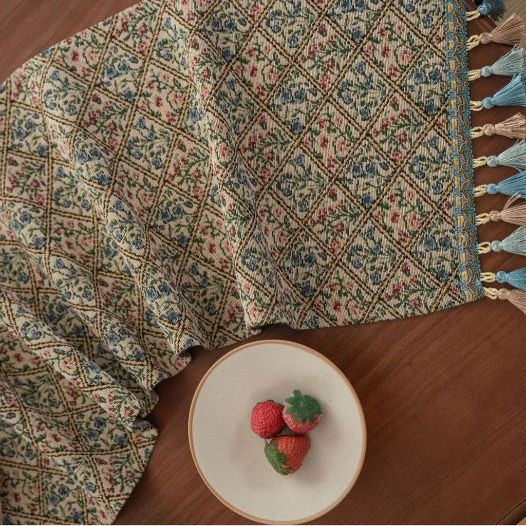Dark blue and white striped jacquard table runner with tassel trim laid on a wooden dining table.
