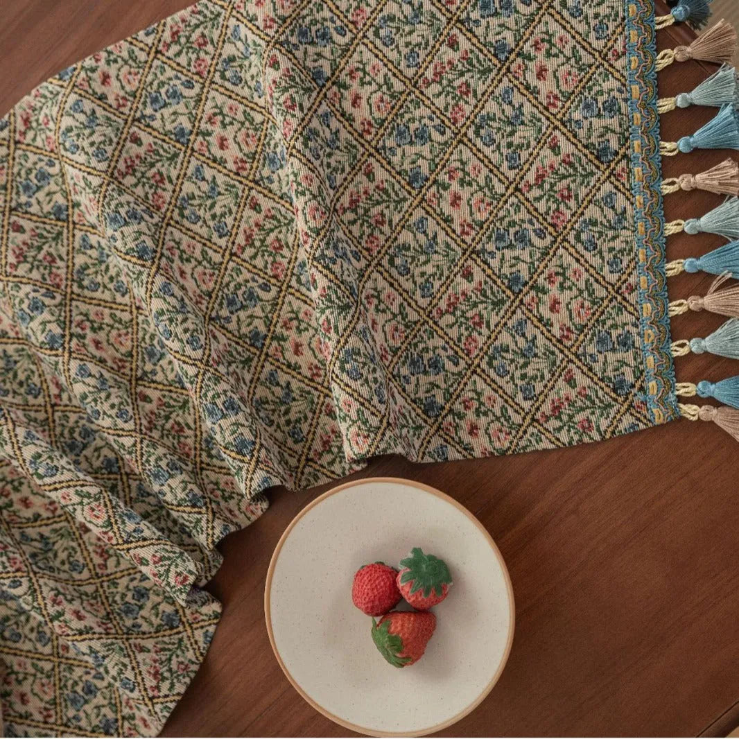 Dark blue and white striped jacquard table runner with tassel trim laid on a wooden dining table.