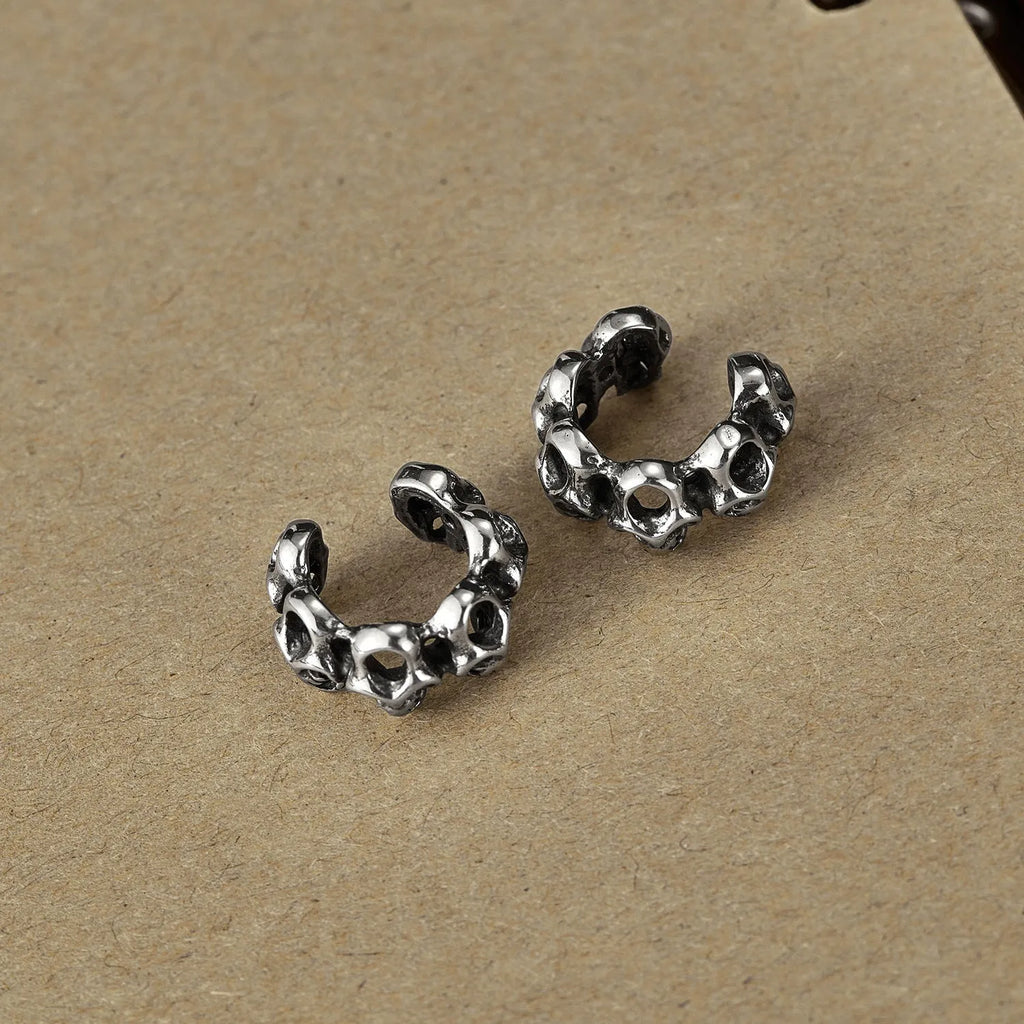 Stainless steel skull earrings with geometric hollow design and clip fitting in metallic finish