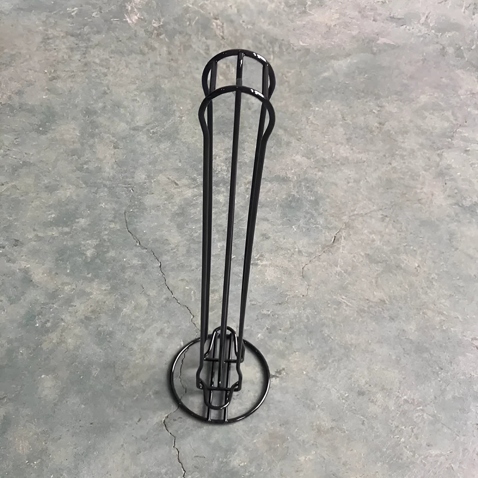 Black wrought iron coffee capsule rack holding 20 pods on display shelves.
