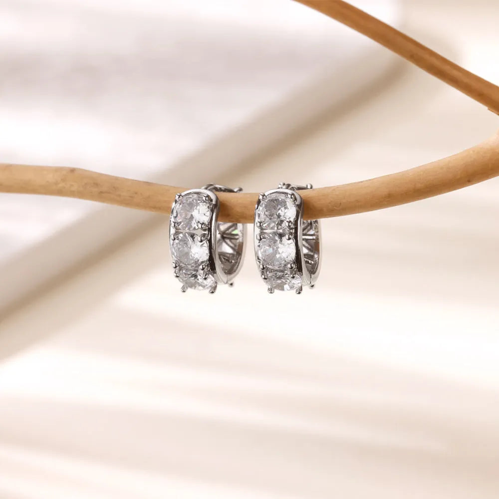 Gold-coloured U-shaped clip earrings with zircon stones on stainless steel background