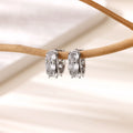 Gold-coloured U-shaped clip earrings with zircon stones on stainless steel background