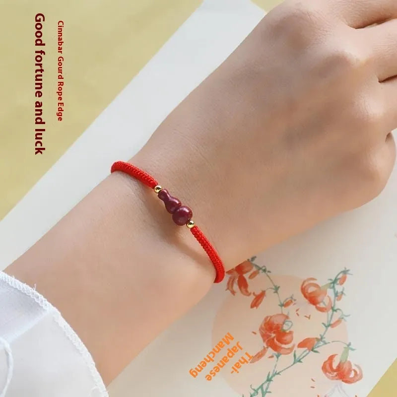 Heart-shaped cinnabar bead on an adjustable knot rope bracelet with a decorative peace buckle closure.