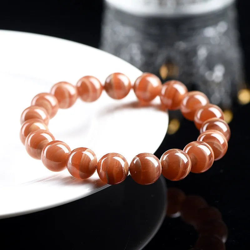 Natural rhodochrosite round bead bracelet with ruyi design on wrist.