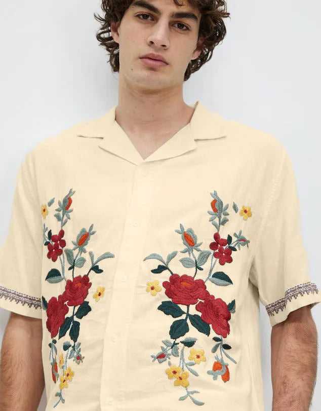 Men's apricot-coloured short-sleeve shirt with vintage floral print and lapel collar on a hanger.