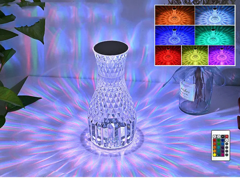 Clear plastic vase-shaped crystal bedside lamp with LED lights on a wooden table.