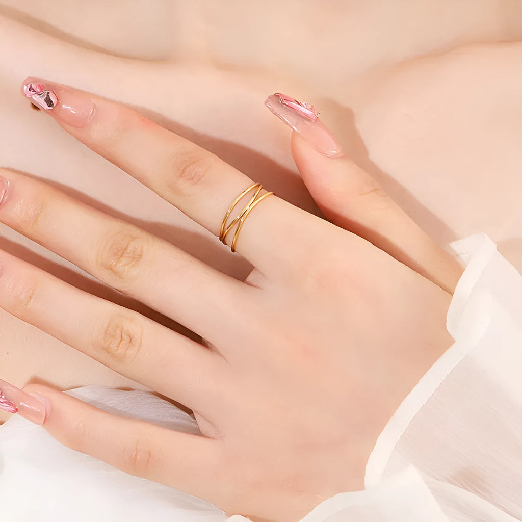 Gold titanium steel ring with a three-layer geometric coil line design on a finger.