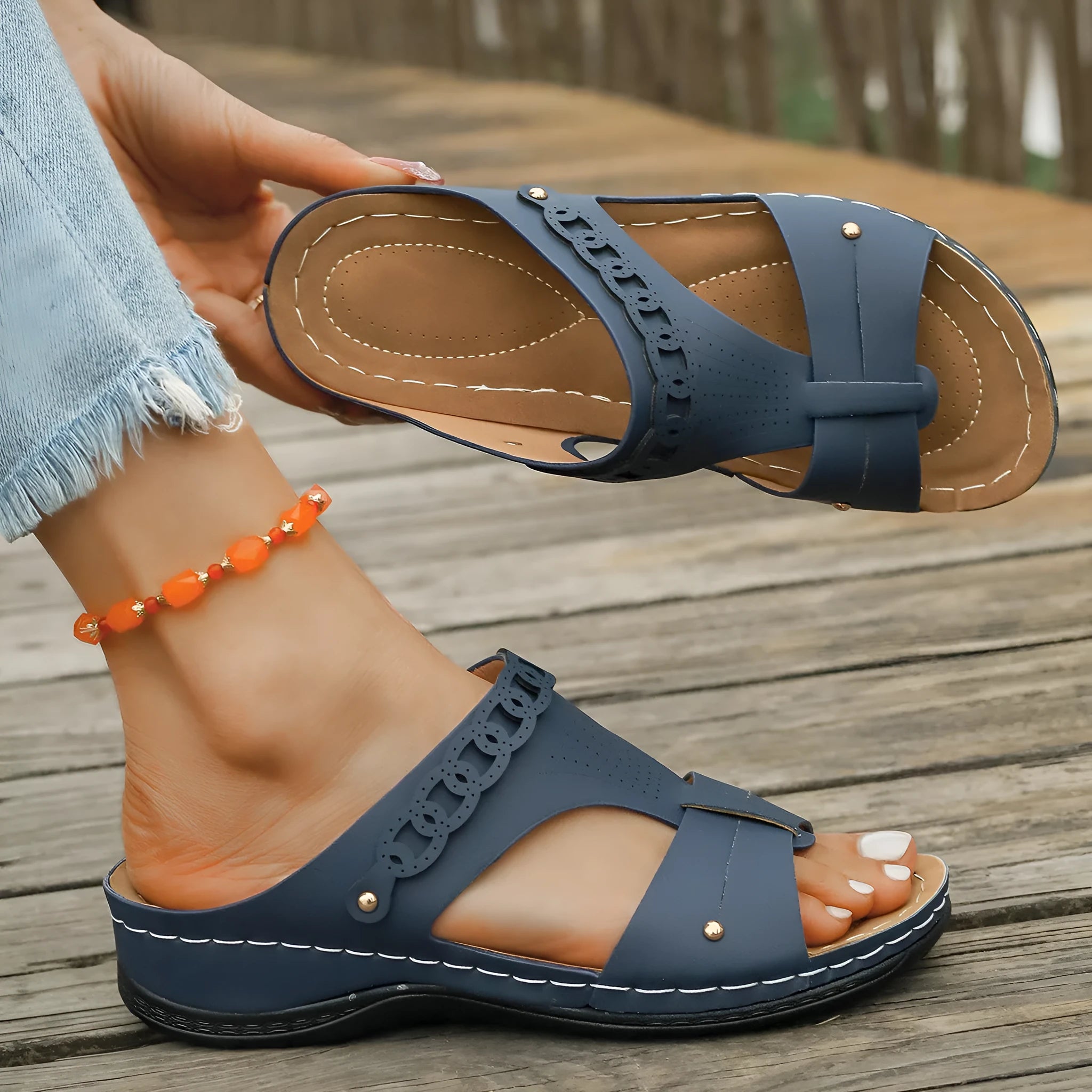 A pair of beige Roman-style slope heel slippers with a fish mouth toe holder on a plain background.
