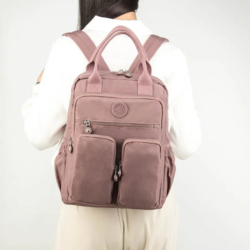 Waterproof women's large capacity nylon travel backpack in multiple colours showing internal laptop compartment and pockets.