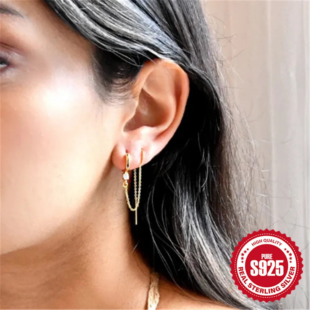Close-up of a women's S925 sterling silver stud earring with a diamond flower, chain, and tassel design in a gold colour.