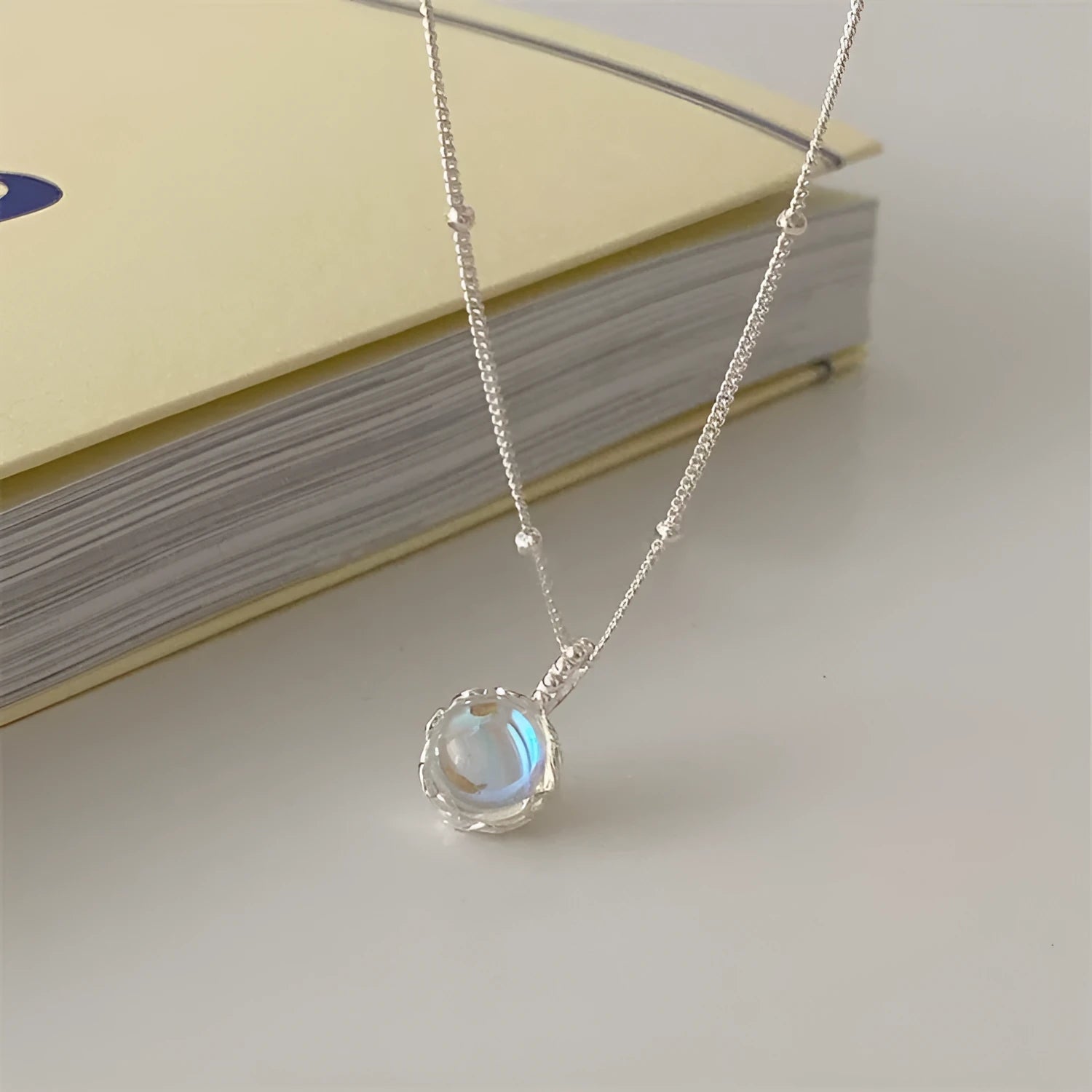 Polished sterling silver necklace for women with round geometric stone pendant on curb chain.