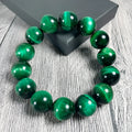 Green Tiger Eye stone beaded bracelet with geometric shaped beads on a wrist.