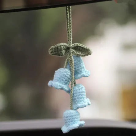 Green and white crochet wool car plant decoration with hanging rope on car dashboard