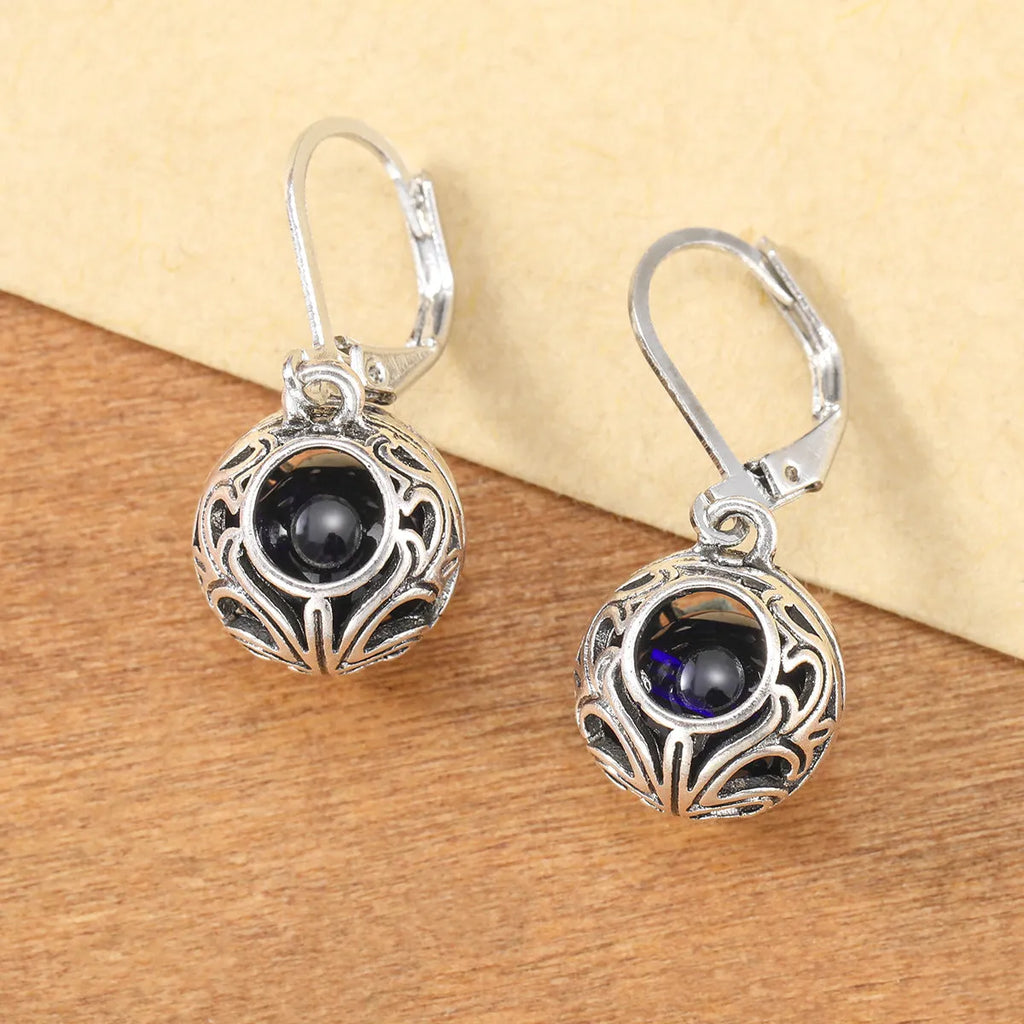 Silver tone pendant earrings with hollow geometric design, blue gemstones, and vintage engraving detail
