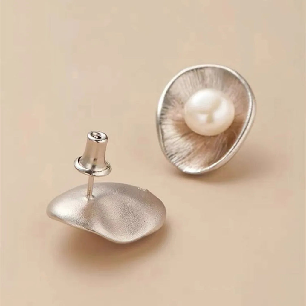 A pair of gold geometric sterling silver ear studs with small white pearl details on a post back.