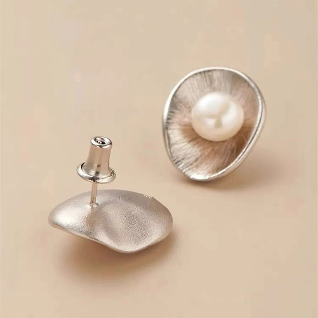 A pair of gold geometric sterling silver ear studs with small white pearl details on a post back.
