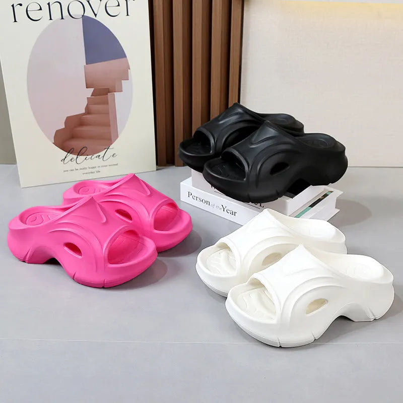 Women's white thick-soled EVA slippers with rounded toe on a sandy beach.