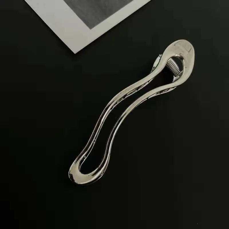 Golden zinc alloy hair barrette in an arc shape on a white background