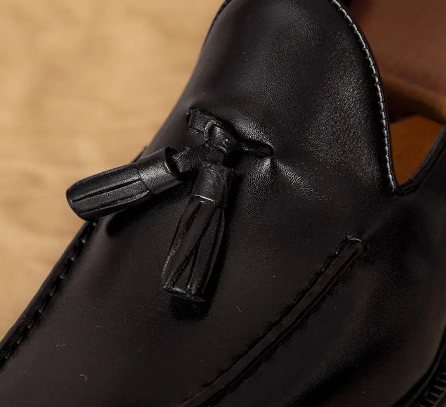 Men's black and brown British-style leather slip-on loafers showing polished leather upper and rubber sole