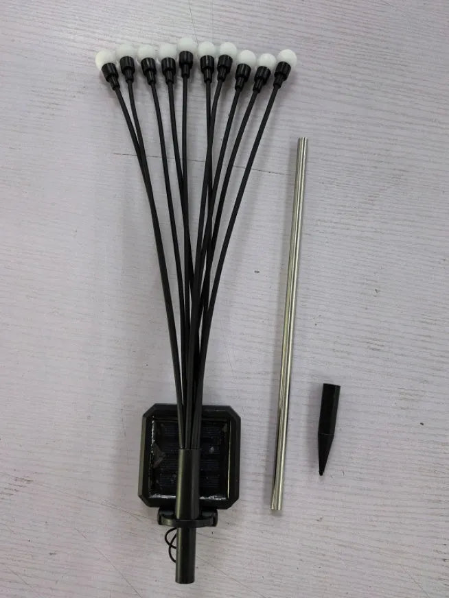 Solar-powered LED firefly lawn light with ground stake inserted in grass