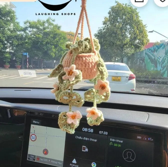 Green and white crochet wool car plant decoration with hanging rope on car dashboard